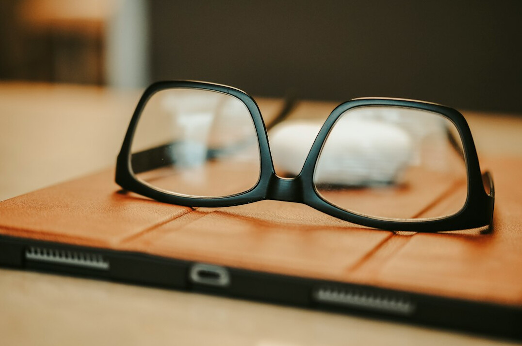 Detective notebook with magnifying glass and old photographs on a wooden desk