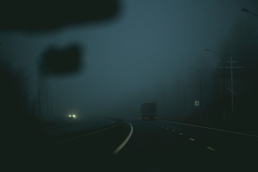 Foggy empty street at night with a single distant silhouette